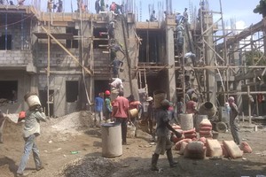 Workers mixing concrete and taking it up to the third floor - bucket-by-bucket..